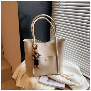 Detailed macro view of cream tote bag with litchi texture and cute plush rabbit charm