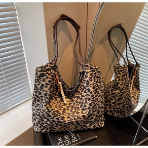 Detail of leopard print tote bag with leather handles and wooden bead tassel decoration