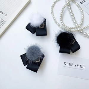 Détail de barrettes noeuds avec pompon en fausse fourrure et boucle en perle carrée