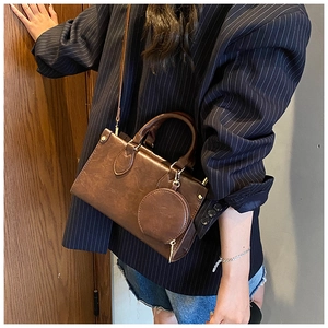 Detail of dark brown vintage crossbody bag with pebbled leather texture and round coin purse