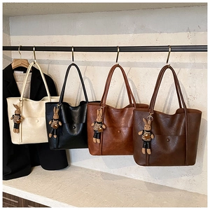 Detail of four colorful tote bags with rabbit charms hanging on a metal rack