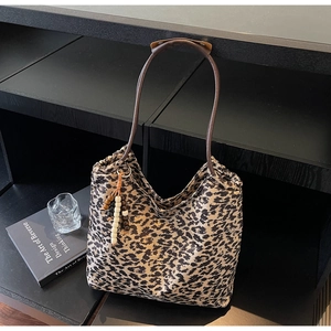 Close-up of leopard print tote bag with brown leather strap and beaded tassel detail