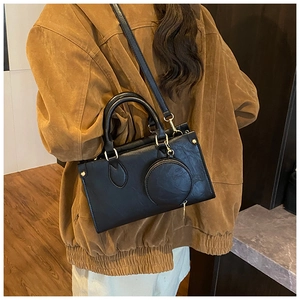 Detail of black PU crossbody bag with detachable round coin purse and gold hardware