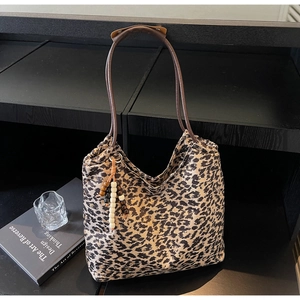 Detail of leopard print tote bag featuring wooden bead charm and brown leather straps