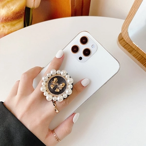 Luxe phone grip with faux pearls and golden bow on white smartphone, lifestyle shot