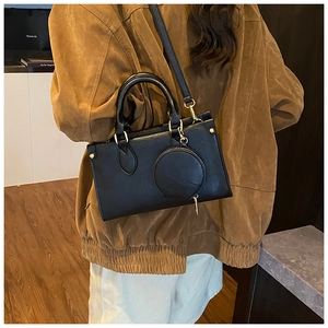 Detail of a black leather crossbody bag with matching round coin purse and gold hardware