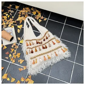 Close-up of white knit tote bag with bohemian colorful tassels and fringe detail