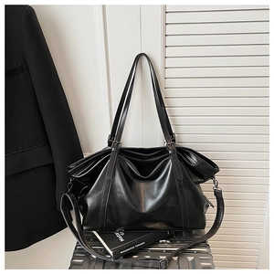 Détail d'un grand sac cabas noir sur une valise montrant la texture en cuir mat