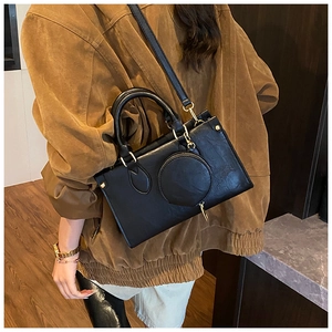 Detail of black faux leather crossbody bag with small round coin purse and gold hardware
