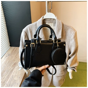 Detail of black rectangular PU leather bag with circular mini coin purse and gold hardware