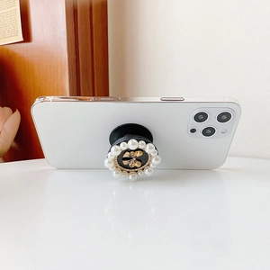 Detail of elegant pearl phone grip with golden bow on a white smartphone back