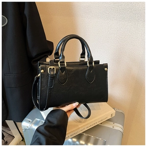 Close-up of black pleated leather tote bag with gold hardware and round handles