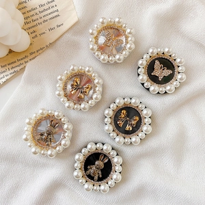 Detail of round phone grips featuring pearl edges with diamond butterfly and rabbit motifs