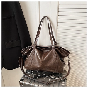 Detail view of vintage dark brown tote bag with leather texture on a metal suitcase