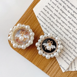 Detail of bee motif with drop pearl on round phone socket holder with pearl rim