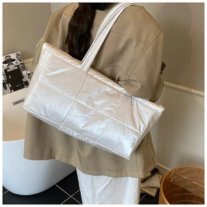 Detail of white quilted oversized tote bag with metallic finish shown on model's shoulder