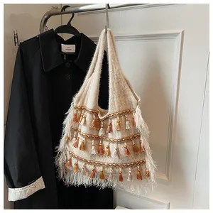 Detail of bohemian cream knit tote bag featuring vibrant orange and brown fringe accents