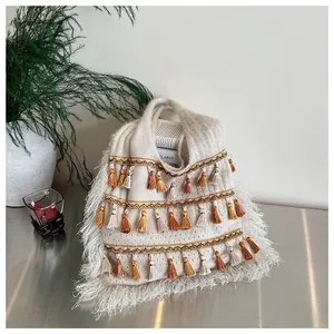 Detail of bohemian knit tote bag featuring colorful fringe and textured cream tassels