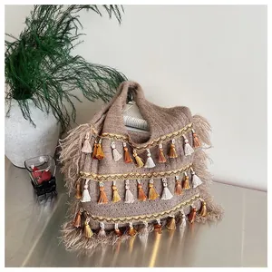 Detail of a brown knit tote bag showing colorful tassels and fluffy plush trim accents