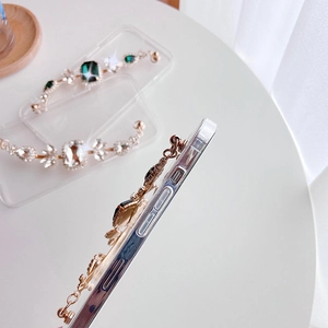 Dettaglio custodia trasparente con catena in pietre preziose dorate e zirconi brillanti