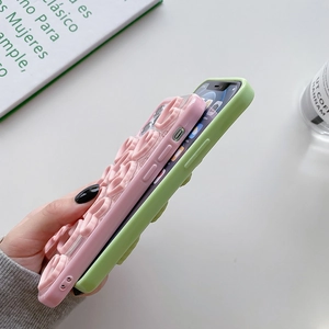 Detail view of pink and green 3D wavy phone cases showing 16 Pro Max camera fit and side grip