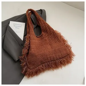 Detailed macro of dark brown knitted tote bag featuring retro fringe and soft wool texture