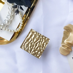 Macro detail of square gold metal phone stand with hammer texture and crystal inlay