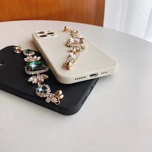 Detail of iPhone case with emerald gemstone wrist strap and rhinestone chain accents
