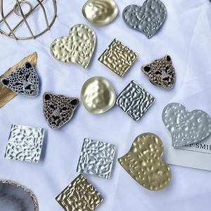 Macro detail of textured gold metal hair clips and panther heads on white fabric