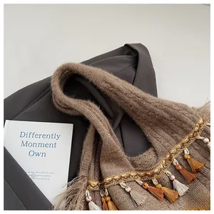 Detail of a brown knitted tote bag featuring wavy gold trim and stylish bicolor tassels
