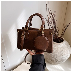 Close-up of retro brown square bag with round coin purse charm and gold metal hardware