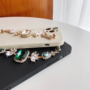 Detail of luxury iPhone case with emerald gemstones and sparkling diamond chain decoration
