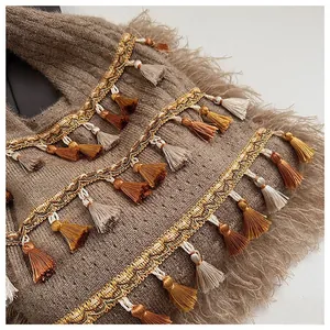 Macro view of brown knit tote with golden woven lace and colorful bohemian tassels