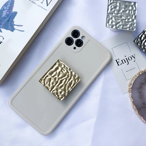 Detail of square hammered metal phone grips in gold and silver on a minimalist case