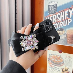 Close-up of black satin bow case for iPhone with colorful crystals and metal ring
