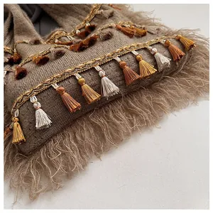 Detailed close-up of textured knit fabric with fringe tassels and woven straps