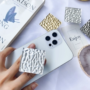 Close-up of square hammered metal phone socket stand in silver and gold plating