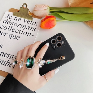 Detail of luxury iPhone case featuring emerald gemstone chain and rhinestone hand strap