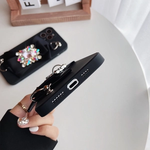 Close-up of matte black iPhone case with colorful jeweled bow and precise port cutouts