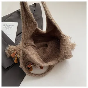 Close-up of brown knit tote bag showing rich woven texture and fringe tassels