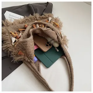 Detail of brown knitted tote bag showing spacious interior with tassels and bohemian charms