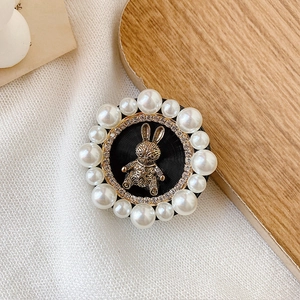 Detailed close-up of a luxury pearl and rhinestone rabbit phone grip on a wooden tray