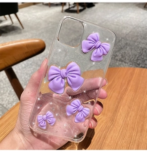 Detail of transparent phone case with purple 3D bows and silver glitter accents