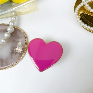 Detail of pink heart-shaped phone grip with gold metallic edge on luxury display