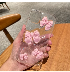 Detail of pink 3D bows and silver glitter inside a clear soft phone case for iPhone