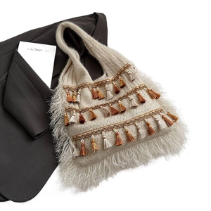 Beige knitted tote bag with multi-color tassels on a grey blazer for bohemian style