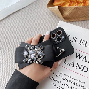 Elegant black silicone iPhone case with a large satin bow and sparkling crystal cluster