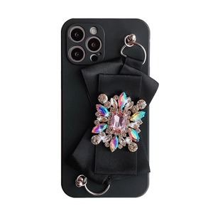 Matte black iPhone case featuring a large satin bow and a luxury crystal gem brooch decoration