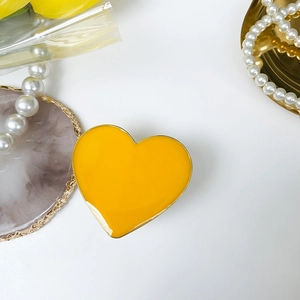 Close-up of a yellow heart-shaped phone grip with gold metallic edges on a stylish desk