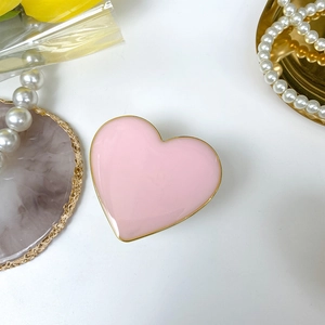 Close-up of pink heart phone grip with gold trim on elegant marble and pearl background
